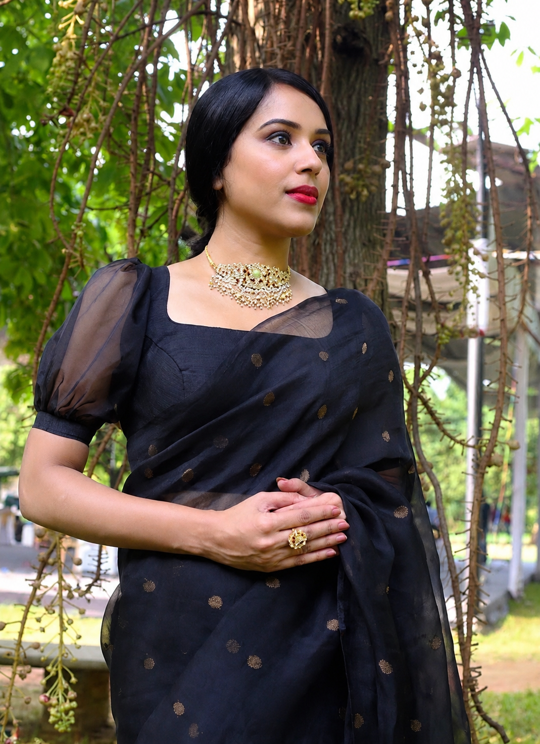Woman wearing a black saree with gold patterns in an outdoor setting